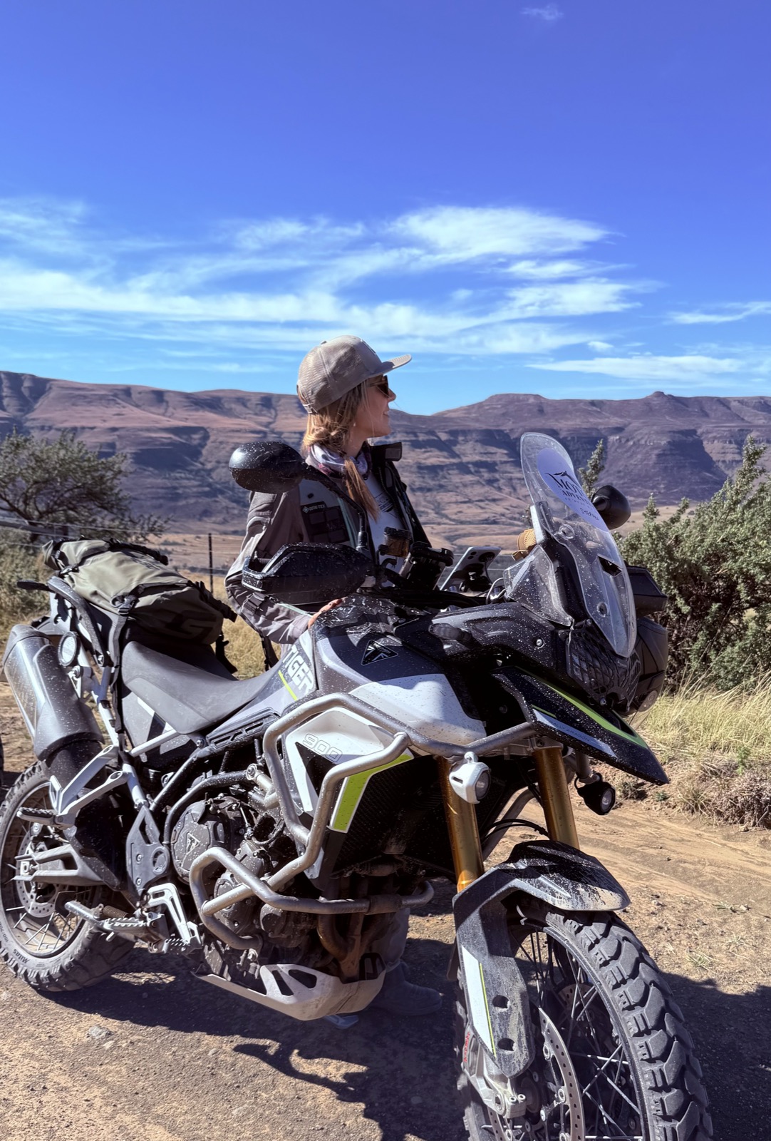 Franziska with her adventure motorcycle, looking out towards the mountains