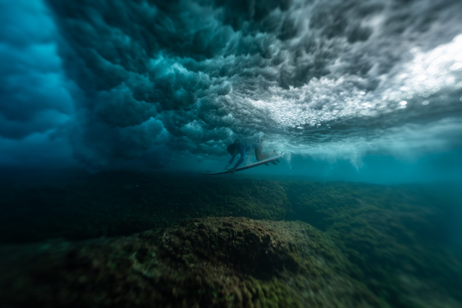 A surfer beneath a breaking wave in the ocean
