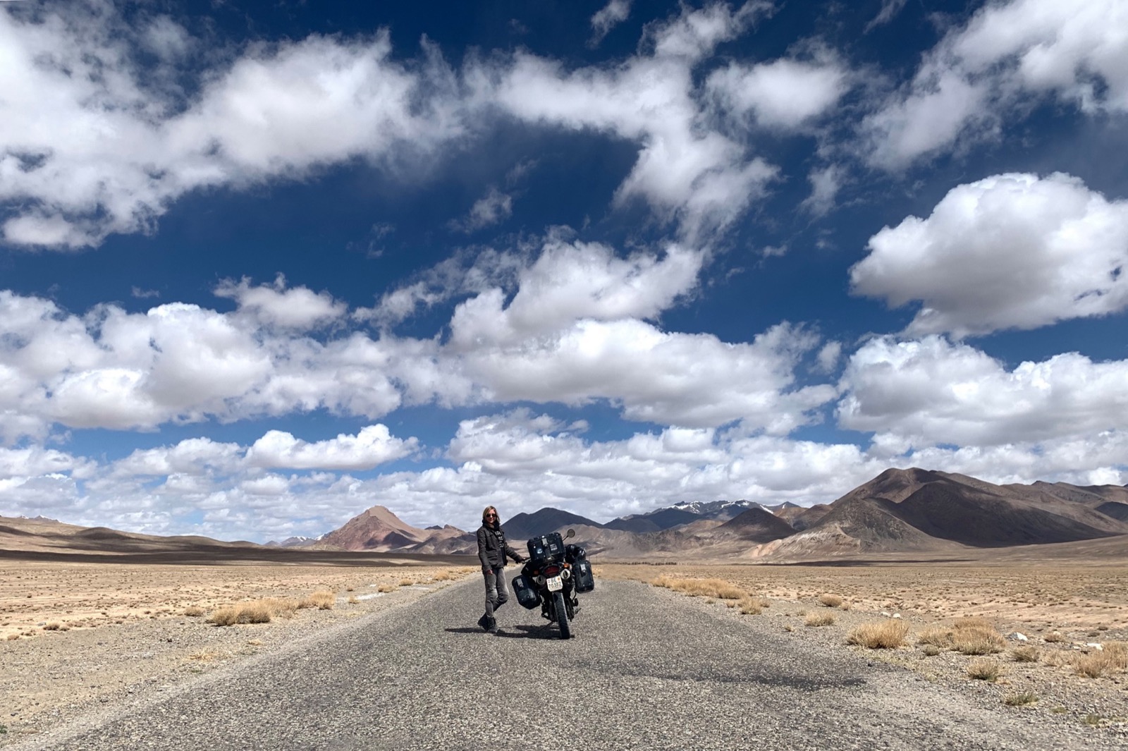 Franziska and her motorcycle on an open mountain road in Tajikistan